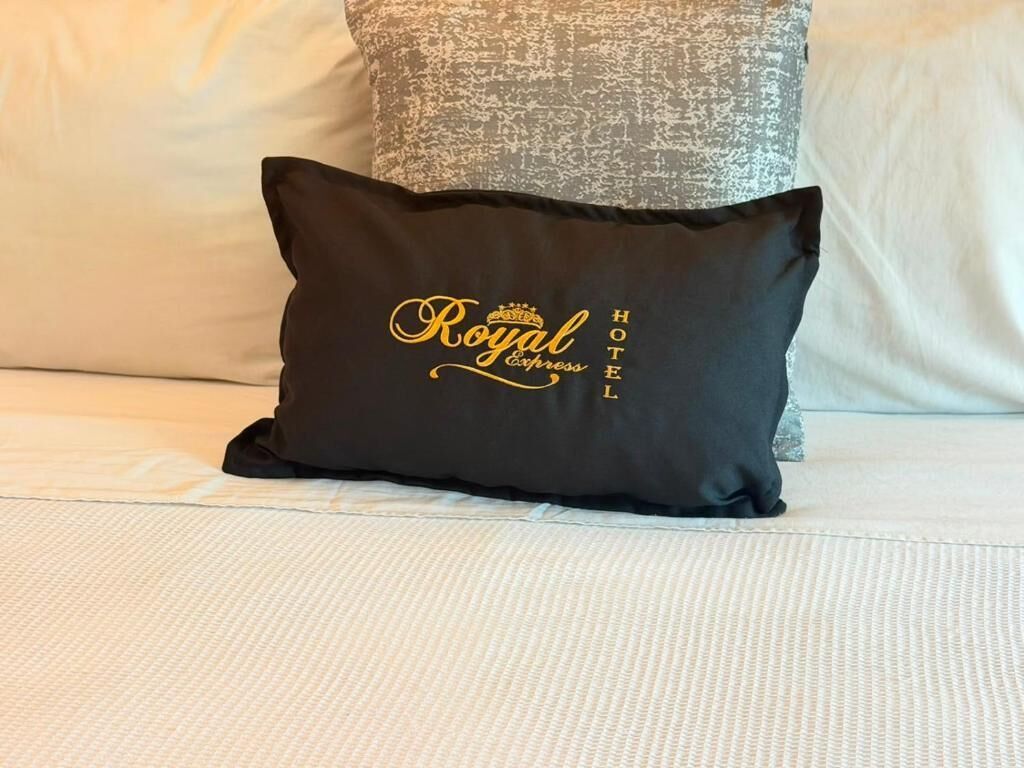 A black pillow with 'Royal Express Hotel' text on a bed.