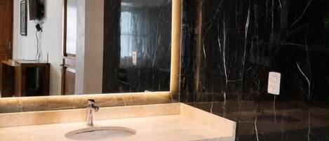 A bathroom with a marble sink, a large mirror, and a wooden ceiling.