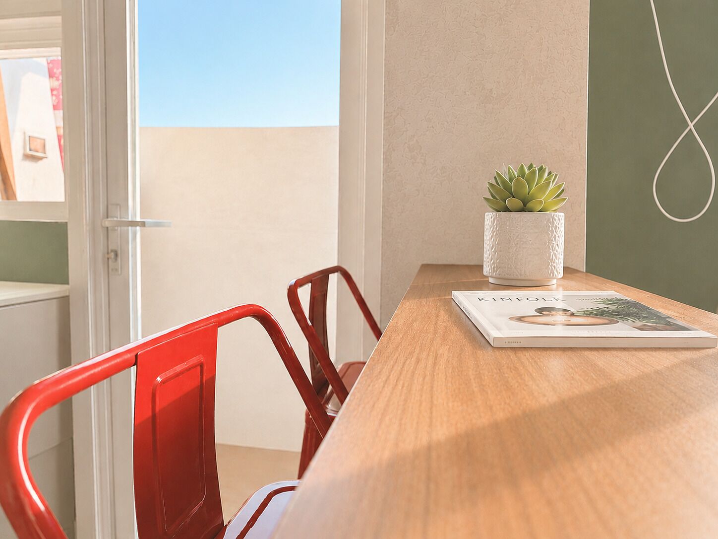 Ein Zimmer mit Holztisch, Topfpflanze und roten Stühlen.