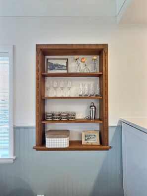 A wooden shelf with various items including framed photos, glassware, and a cocktail shaker. - Peach House - 7 Mins to Cedar Point (Sandusky)
