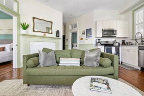 Ein Wohnzimmer mit einem grünen Sofa, einem weißen Couchtisch und einem Kamin.