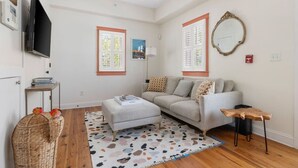 Una sala de estar moderna con un sofá, un reposapiés y un televisor.