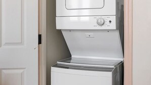 A compact washer and dryer unit in a small, enclosed space with a wooden door frame. - 2BR Spring Street Escape - D (Charleston)