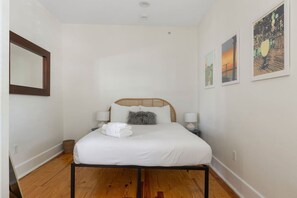 Ein Schlafzimmer mit einem Bett, zwei Nachttischlampen, einem Spiegel und einem Wandbild.