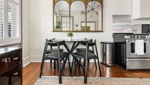 A dining area with a table and chairs, a large mirror, and a kitchen with appliances. - 2BR Historic Charleston Getaway - C (Charleston)