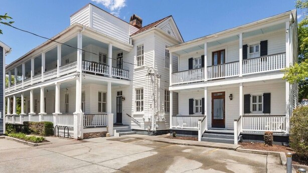 A two-story white building with balconies, a front door, and a small porch area. - 2BR Historic Charleston Getaway - C (Charleston)