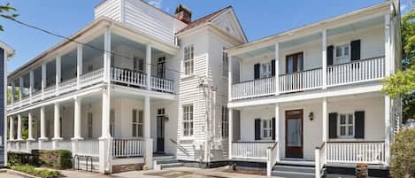 A two-story white building with a porch and a front door.