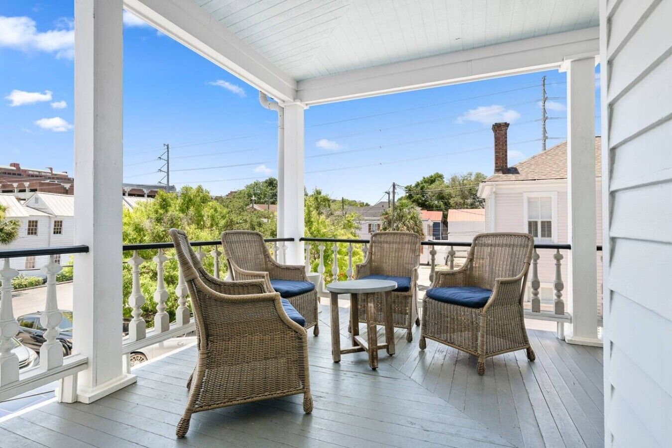 A covered porch with wicker furniture and a view of the neighborhood.