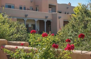 Ein Gebäude mit mehreren Balkonen und einem Garten mit roten Blumen.