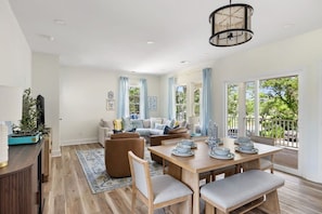 A spacious living area with a dining table set for four, a sofa, and a television. - 4BR New - Close to Folly Beach! (Charleston)