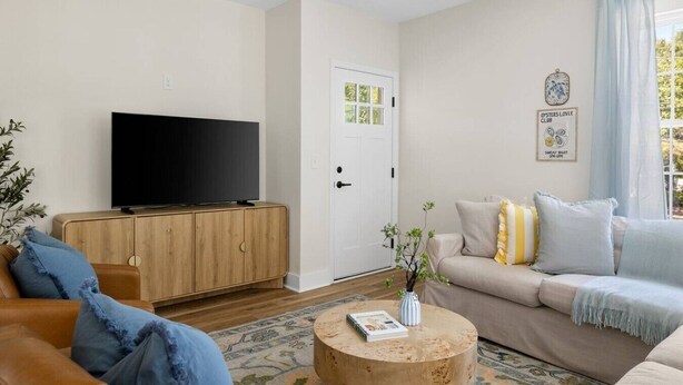 Ein modernes Wohnzimmer mit Flachbildfernseher, Holzschrank, beiger Couch und rundem Couchtisch.