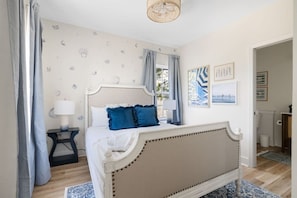 A bedroom with a bed, curtains, a nightstand, a lamp, and wall art. - 4BR New - Close to Folly Beach! (Charleston)