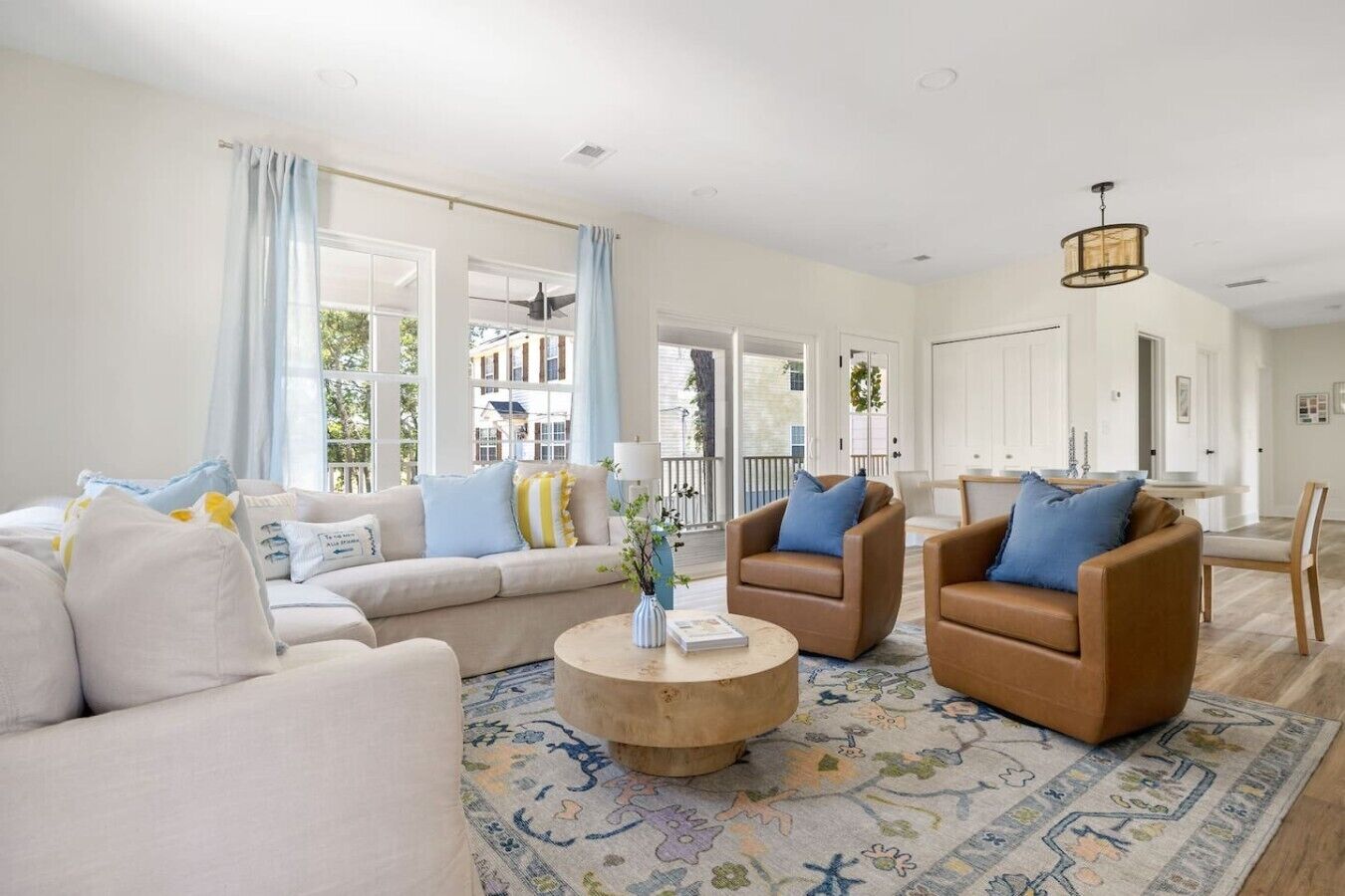 A spacious living room with a sofa, two armchairs, a coffee table, and a patterned rug.