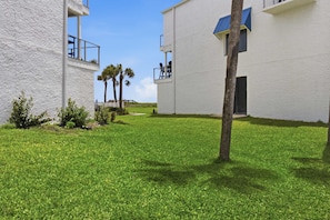 A courtyard with white buildings, a clear sky, and a well-maintained lawn.