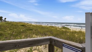 Ein Strand mit einer Holzlattenverkleidung und einem Schild, das die aktuellen Strandverhältnisse anzeigt.