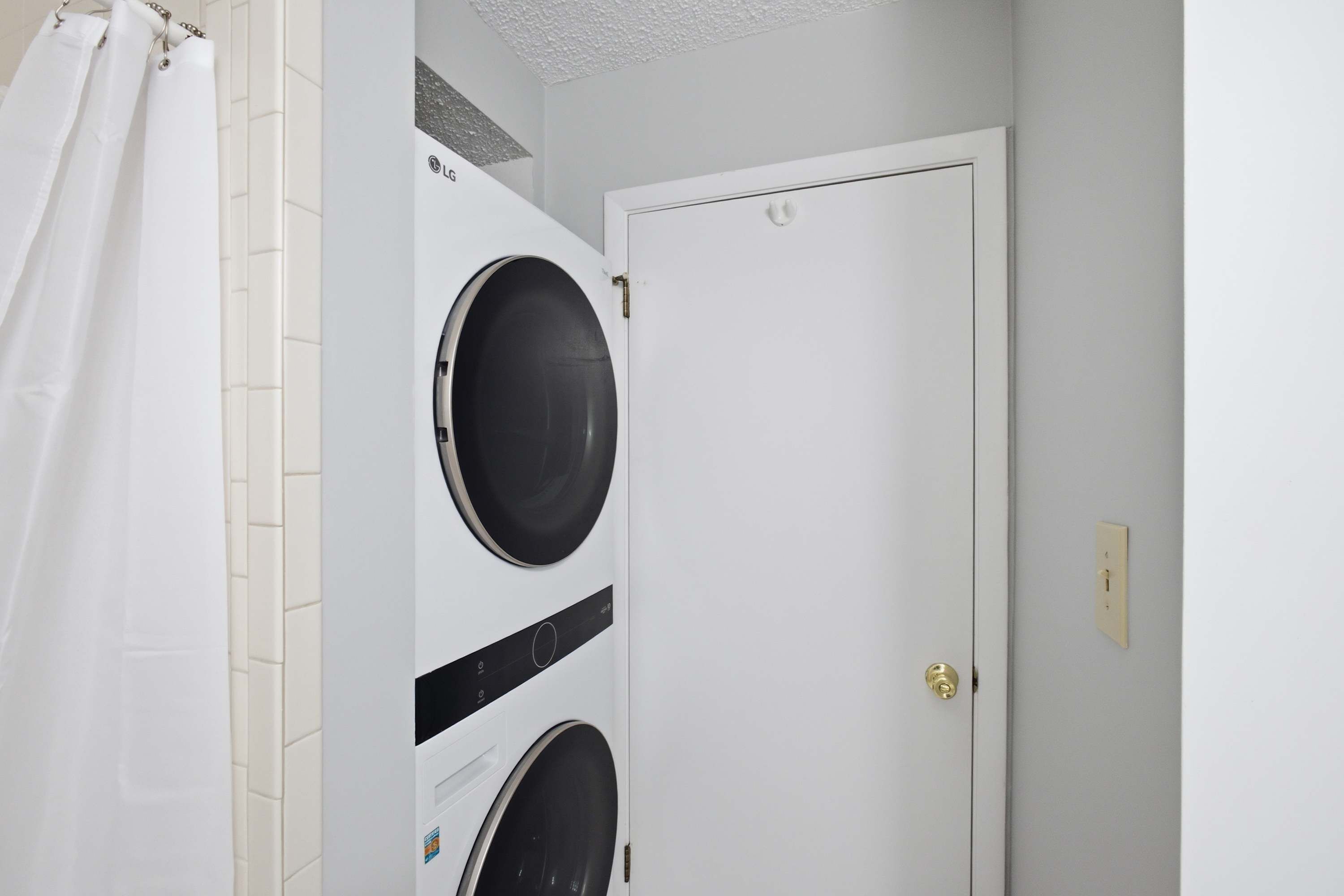A laundry room with a white door, a washing machine, and a shower curtain.