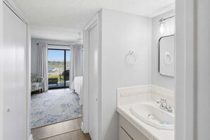 A hotel room with a balcony, a bathroom with a sink and mirror, and a view of the outside.