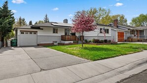 A single-story house with a garage, a front yard with a small tree, and a flag. - Sleek & Modern 1BR/1BA Reno Home (Reno)
