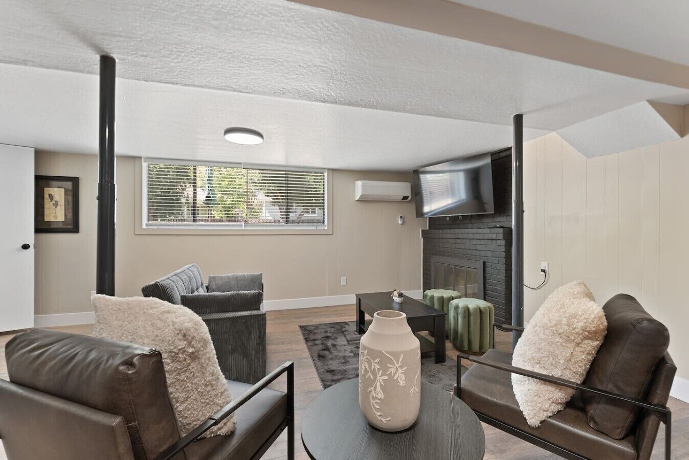 A modern living room with a fireplace, comfortable seating, and a large window.