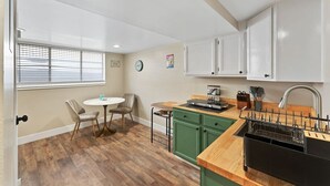 A compact kitchen with a dining area, wooden flooring, and a window with blinds. - Sleek & Modern 1BR/1BA Reno Home (Reno)