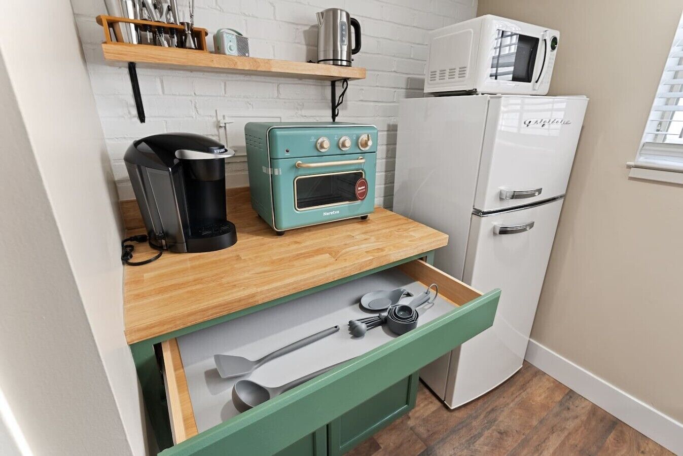 A compact kitchenette with a vintage-style toaster, a coffee maker, a microwave, and a refrigerator.