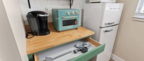 A compact kitchenette with a vintage-style toaster, a coffee maker, a microwave, and a refrigerator.