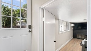A hallway with a white door, a window, and a fireplace. - Sleek & Modern 1BR/1BA Reno Home (Reno)