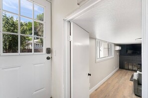 A hallway with a white door, a window, and a fireplace.