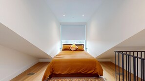 Una camera da letto moderna con un'ampia finestra, un letto con copriletto marrone e una ringhiera nera.