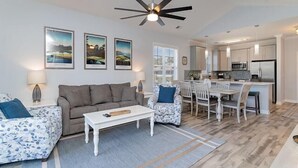 A modern living room with a sofa, coffee table, and a dining area with chairs and a table. - Golf, Pool & Coastal Comfort Willow Bend 234 (North Myrtle Beach)