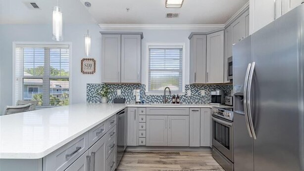 A modern kitchen with a central island, stainless steel appliances, and a tiled backsplash. - Golf, Pool & Coastal Comfort Willow Bend 234 (North Myrtle Beach)