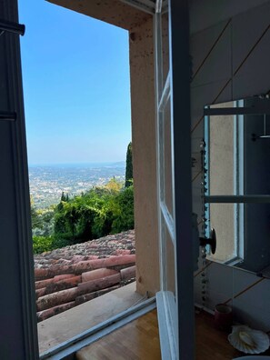 Eine geöffnete Tür, die zu einem Balkon mit Blick auf die Stadt führt.