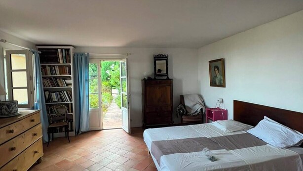 A bedroom with a bed, a dresser, a chair, a desk, a bookshelf, and a door leading to an outdoor area. - Stunning villa with a pool and ocean view, Mediterranean garden, sleeps 8 (Grasse)
