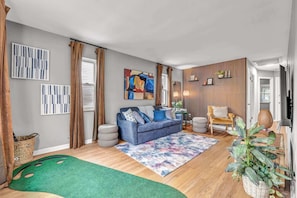 A modern living room with a sofa, a coffee table, a rug, and a plant. - 4BR - Lakewood Duplex - Near Cleveland + Lake Erie (Lakewood)