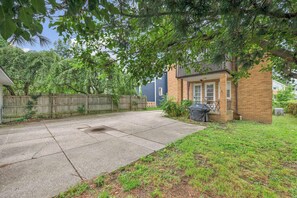 A residential backyard with a concrete patio, a wooden fence, and a brick house. - 4BR - Lakewood Duplex - Near Cleveland + Lake Erie (Lakewood)