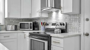 Una cocina moderna con armarios blancos, electrodomésticos de acero inoxidable y salpicadero de azulejos.