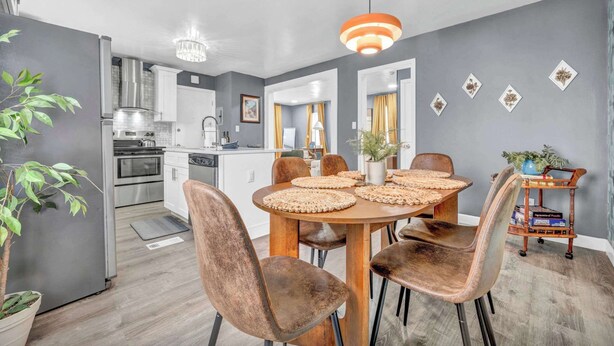 Una cocina moderna con gabinetes blancos, electrodomésticos de acero inoxidable y un comedor con una mesa redonda y sillas.