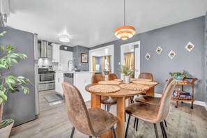 A modern kitchen with white cabinets, stainless steel appliances, and a dining area with a round table and chairs. - 4BR - Lakewood Duplex - Near Cleveland + Lake Erie (Lakewood)