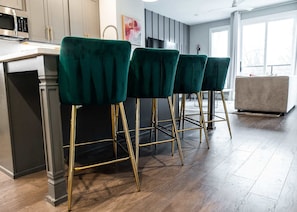 A modern kitchen with a bar area, featuring green bar stools with gold legs. - East Nashville Social House | Sleeps 10 + Deck (Nashville)