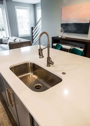 A kitchen with a stainless steel sink, a curved faucet, and a white countertop. - East Nashville Social House | Sleeps 10 + Deck (Nashville)