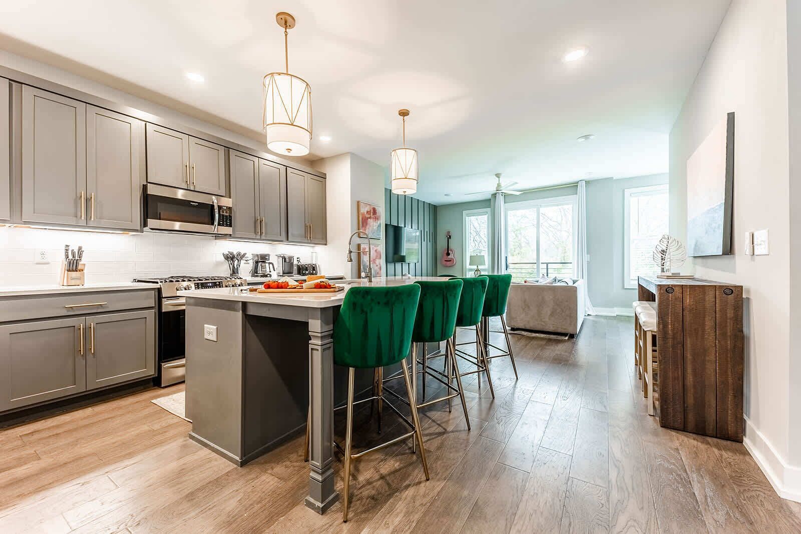 A modern kitchen with grey cabinets, a central island, and green bar stools.