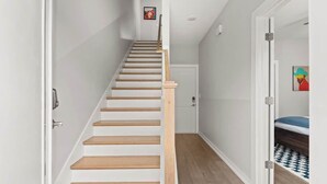Eine Treppe mit Holzbodenstufen und weißen Wänden, die zu einer Tür oben führt.