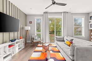 A modern living room with a sofa, a coffee table, and a TV on the wall. - Nashville Pop Art 4BR, Near Downtown and Sleeps 10 (Nashville)
