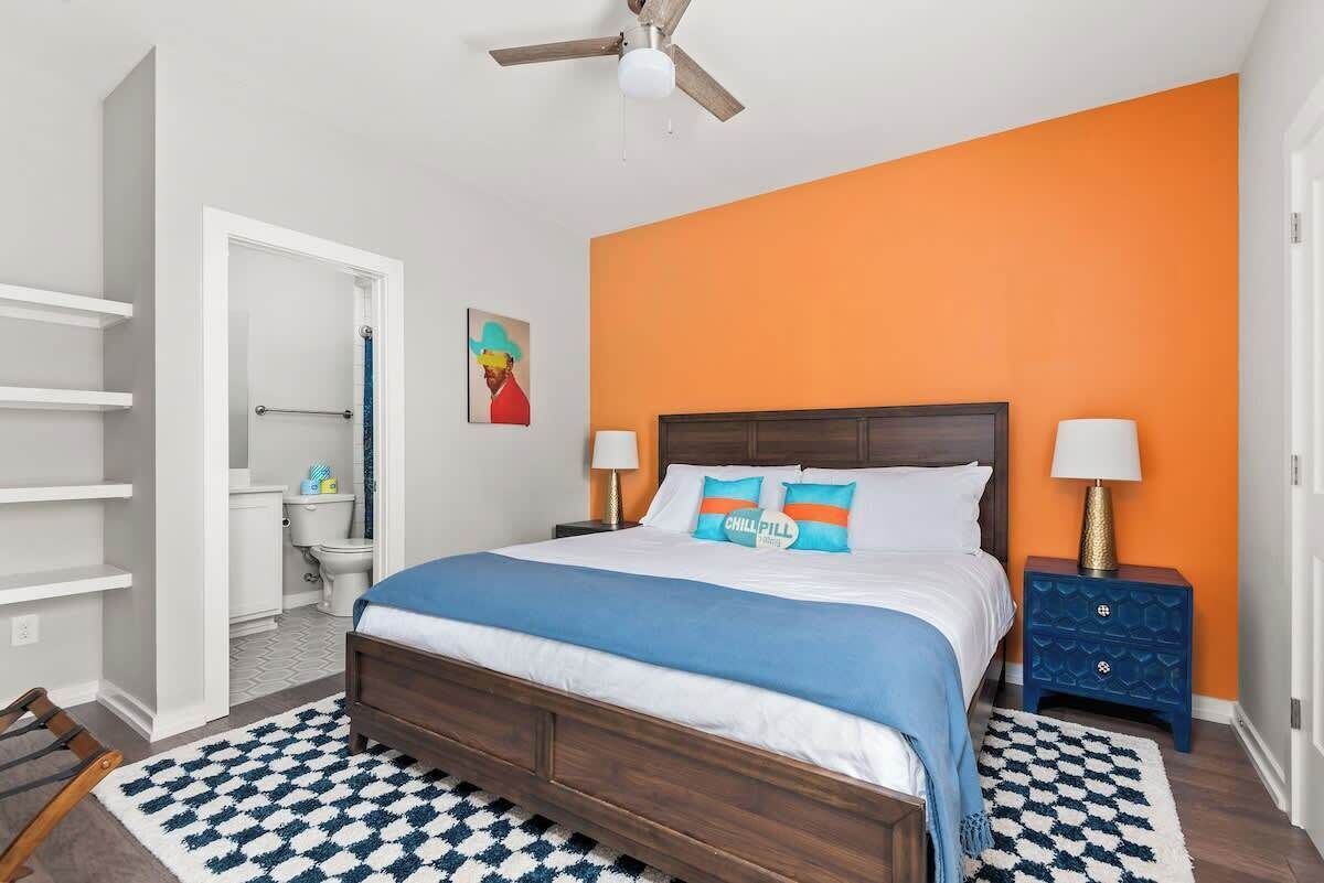 A bedroom with a bed, two bedside tables, a ceiling fan, and a bathroom visible through an open door.
