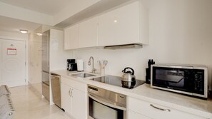 A modern kitchen with stainless steel appliances, a microwave, and a kettle. - Beachfront 1BR Apartment on Ocean Drive (Miami Beach)