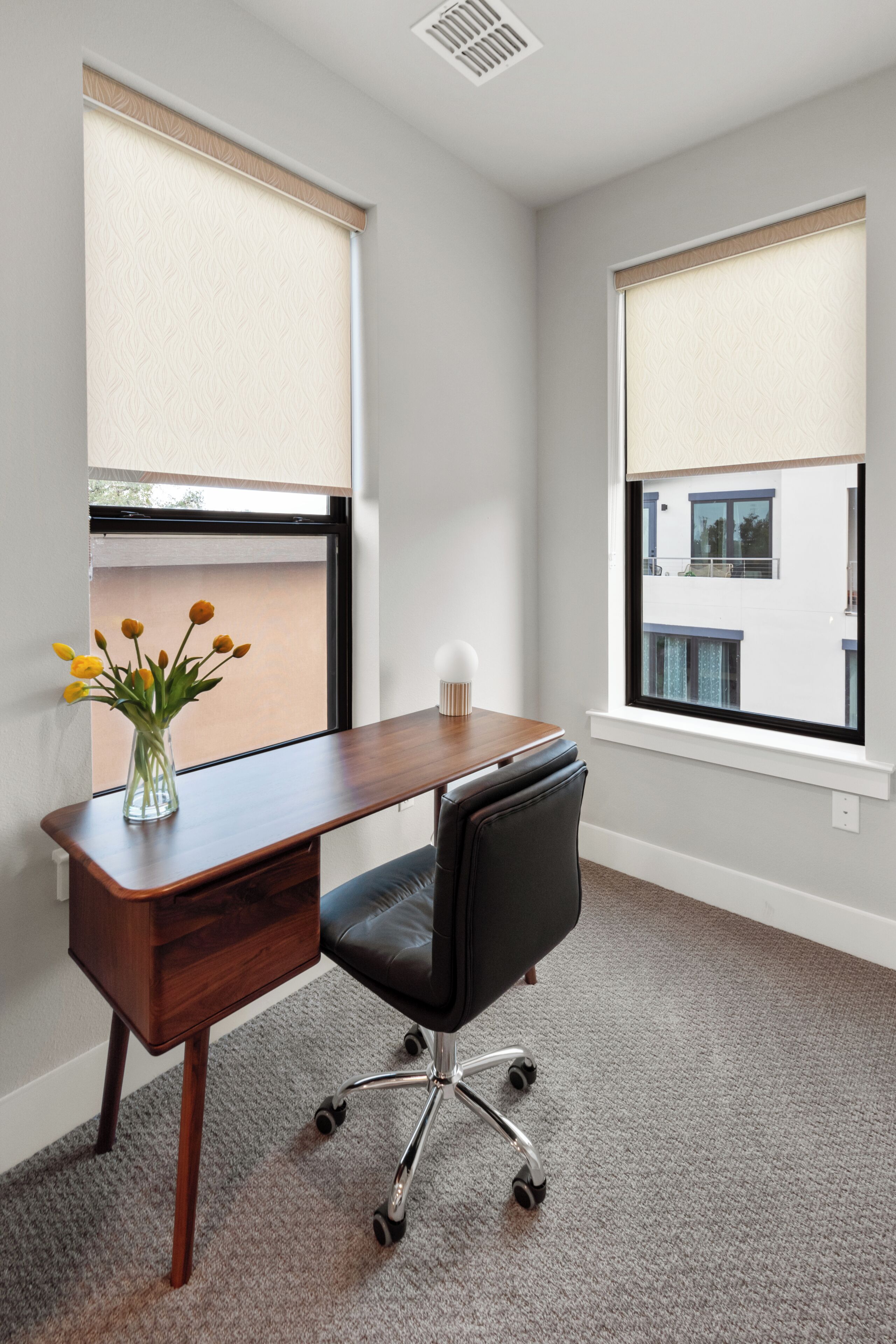 A room with a desk, chair, and a window with blinds.