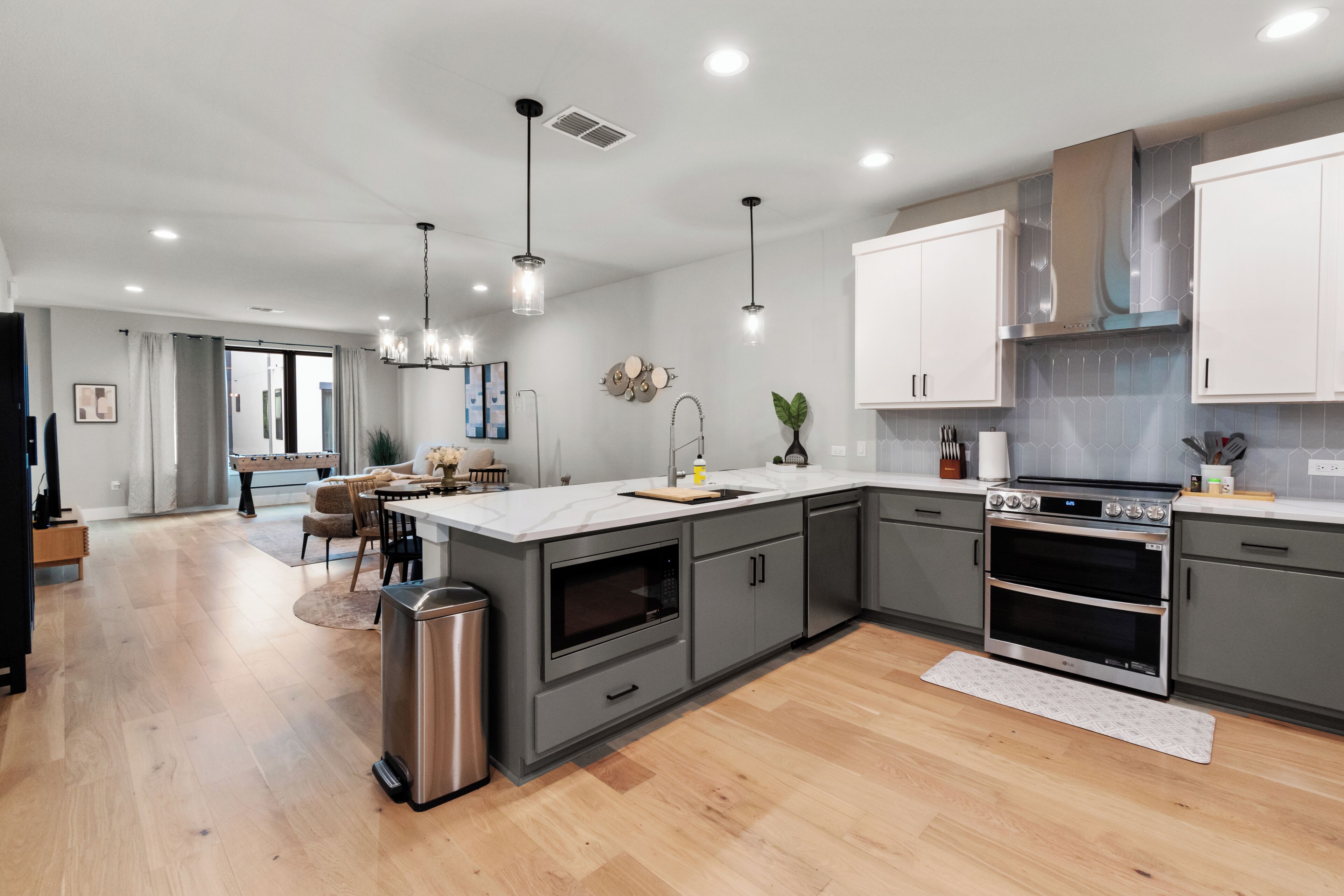 A modern kitchen with grey cabinetry, stainless steel appliances, and a central island.