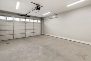 A garage with a white garage door, a ceiling-mounted projector, and a clean, empty concrete floor. - Cozy 2-bedroom townhome in peaceful Austin with AC (Austin)