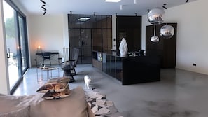 A modern living room with a sofa, a dining area with chairs, and a kitchen with a black countertop.