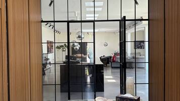A modern interior with a glass partition, a marble-top table, and a skylight.